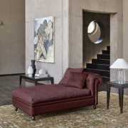 Showroom moderne avec chaise longue marron, œuvres d'art abstraites et vitrine circulaire. Découvrez un décor minimaliste avec des murs en béton gris qui respirent la qualité et le style. Canape Paris by Atelier Bis