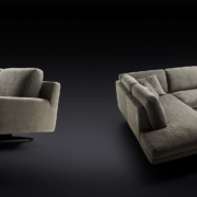 Un design moderne est mis en valeur avec deux canapés sectionnels gris foncé, ou canapé, ornés de coussins sur fond noir, rappelant un showroom parisien chic. Canape Paris by Atelier Bis