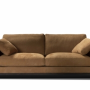 Canapé en daim marron avec deux coussins de chaque côté, posé sur un fond blanc, dégageant une élégance de qualité showroom. Canape Paris by Atelier Bis