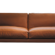 Un canapé en cuir marron avec accoudoirs carrés et deux coussins d'assise, sur fond blanc immaculé, incarne l'élégance d'un showroom parisien. Canape Paris by Atelier Bis