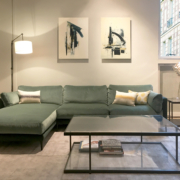 Un salon moderne et sophistiqué à Paris, doté d'un luxueux canapé vert, de peintures abstraites, d'une élégante table basse en verre et d'un élégant lampadaire. Canape Paris by Atelier Bis