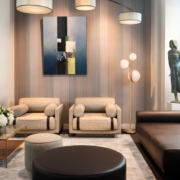 Un salon parisien moderne avec des sièges beiges, de l'art abstrait et un lustre circulaire, avec une sculpture élégamment positionnée sur la droite. Canape Paris by Atelier Bis