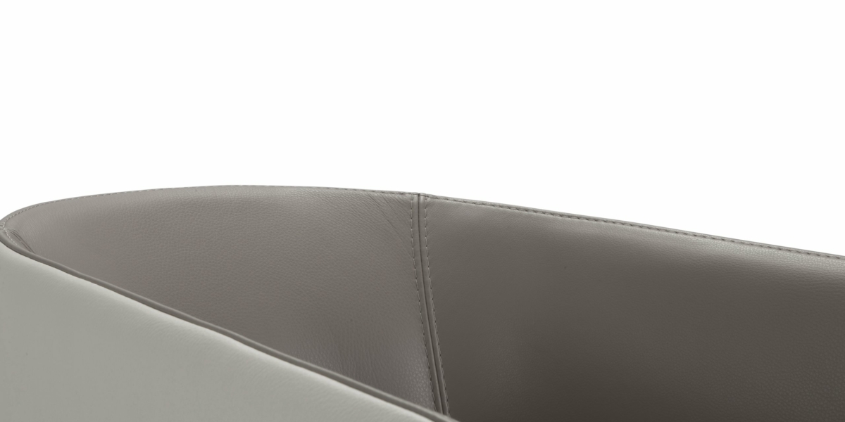 Gros plan sur le bord d'une chaise moderne avec une finition en cuir lisse gris clair, rappelant l'élégance que l'on retrouve dans un showroom parisien. Canape Paris by Atelier Bis