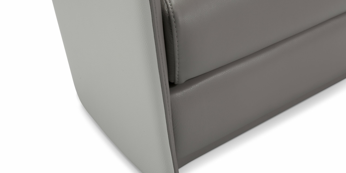 Gros plan d'un canapé d'angle en cuir gris avec des coutures rembourrées et un design minimaliste, parfait pour n'importe quel showroom parisien. Canape Paris by Atelier Bis