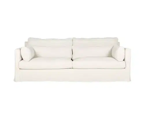 Un canapé moelleux blanc immaculé avec deux coussins se dresse élégamment, rappelant une vitrine d'exposition, sur un fond uni. Canape Paris by Atelier Bis