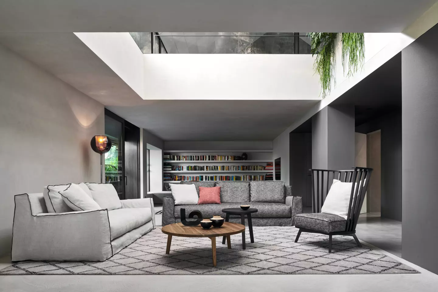 Un salon moderne à Paris avec des canapés gris, une table basse en bois et un tapis géométrique, le tout élégamment éclairé par une lucarne. Un mélange parfait de style et de qualité vous attend dans cette retraite urbaine chic. Canape Paris by Atelier Bis