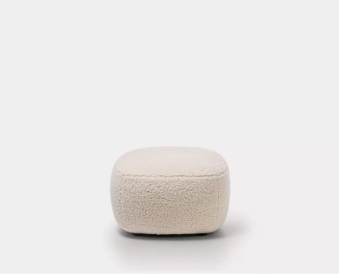 Un pouf doux, rond et beige clair orne un fond blanc uni, reflétant la qualité sans effort que l'on trouve généralement dans un showroom parisien. Canape Paris by Atelier Bis