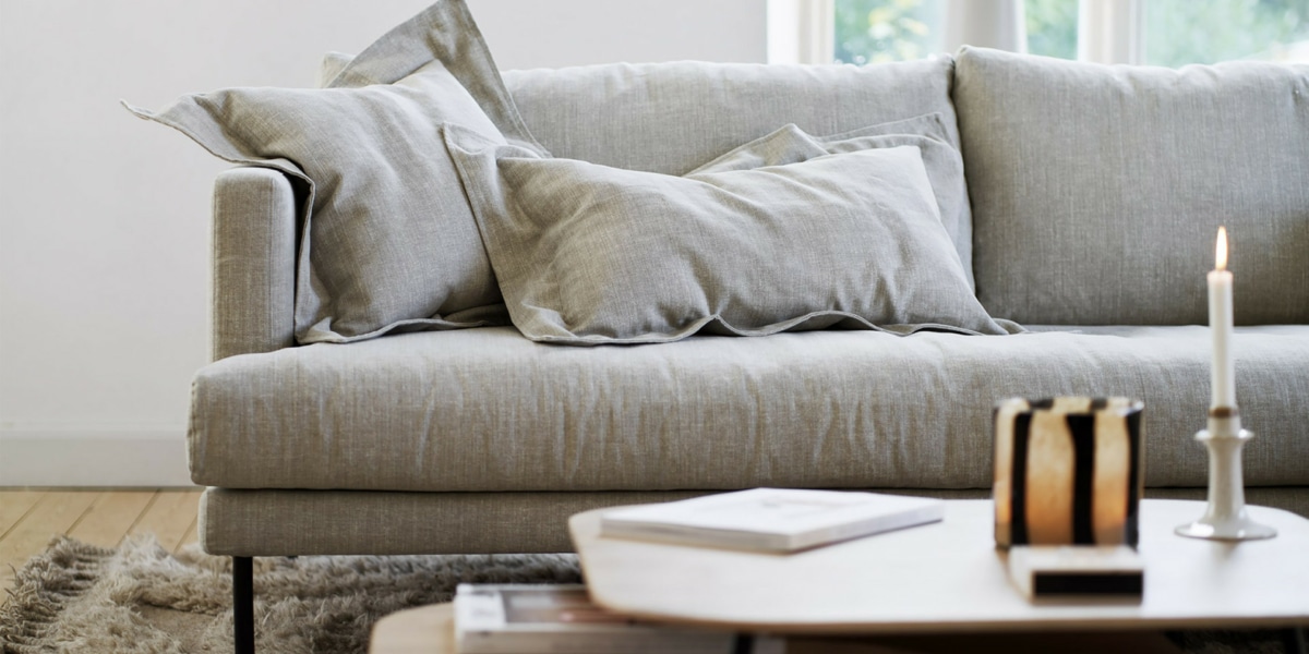 2_BRITT_interior_set2_caleido_stampato_1_natur_3 Un espace moderne avec un canapé modulable gris foncé, des meubles laqués blancs et un éclairage LED.