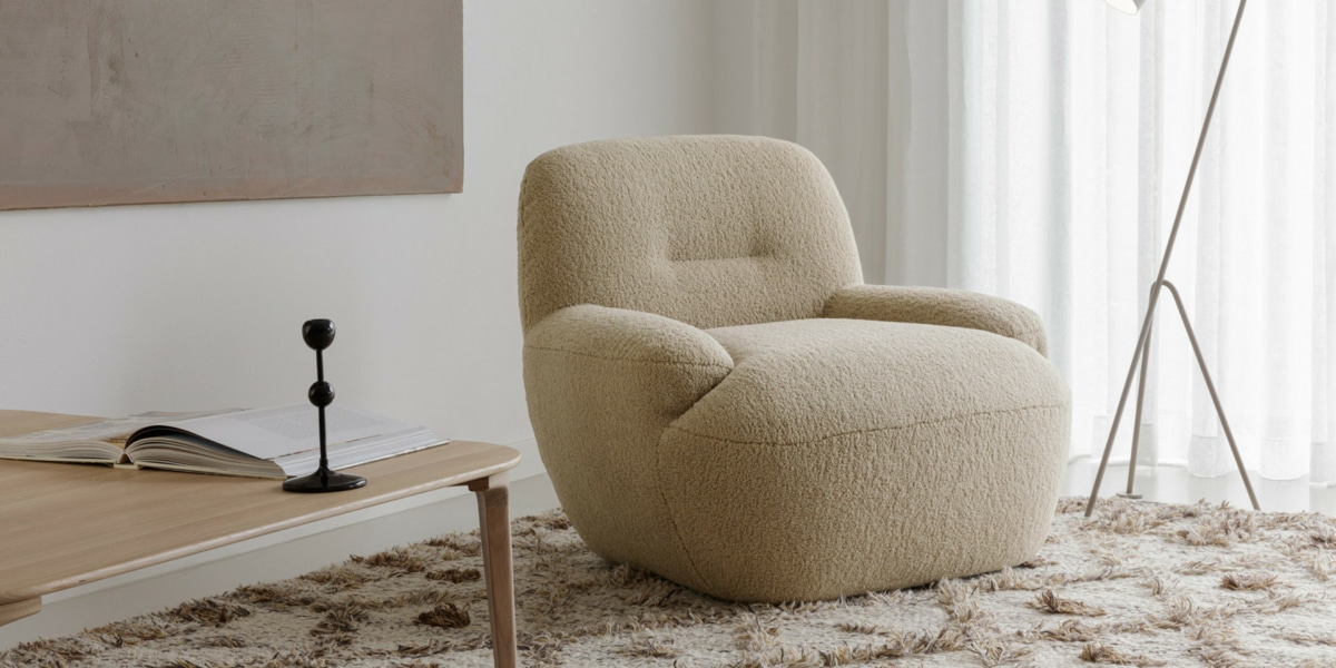 2_UMA_interior_armchair_poodle_3_beige_2 Fauteuil Uma en cuir marron foncé avec des coussins jaunes et blancs Le fauteuil en cuir marron foncé est orné de coussins jaunes et blancs, créant un contraste subtil et élégant dans le salon lumineux.