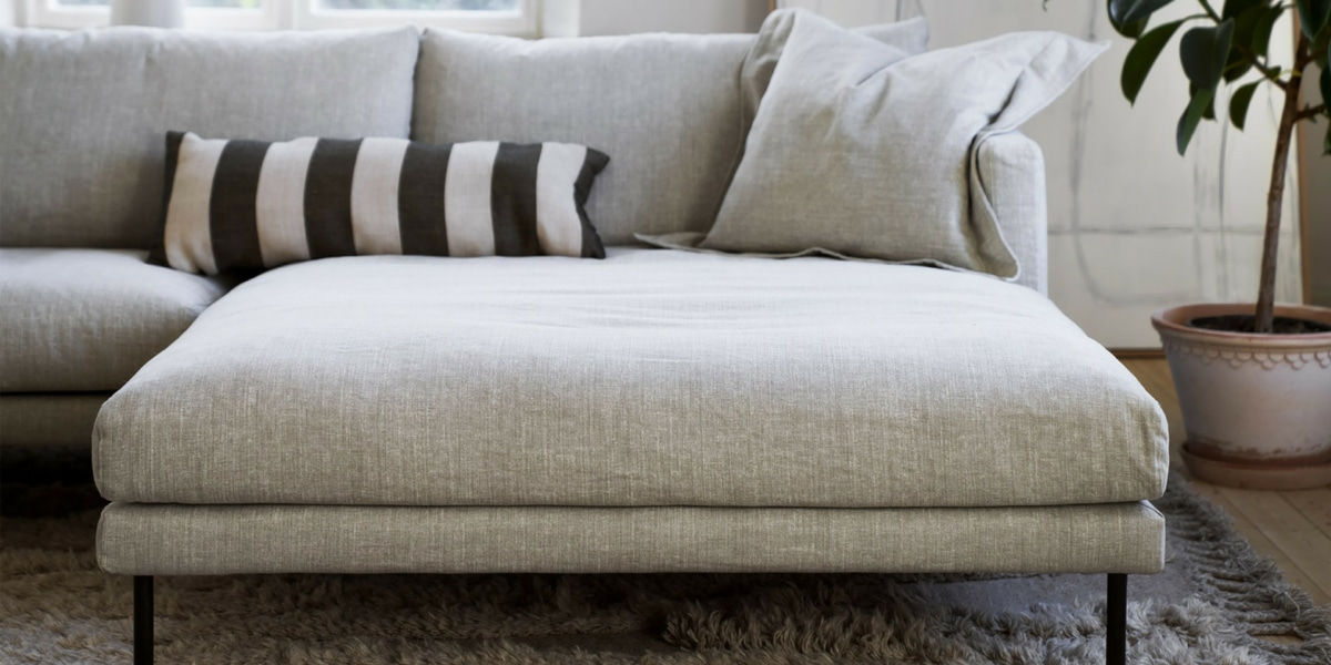 4_BRITT_interior_set2_caleido_stampato_1_natur_2 Un salon vintage avec un canapé en tissu à motifs, une table basse en bois recyclé et des accessoires rétro.