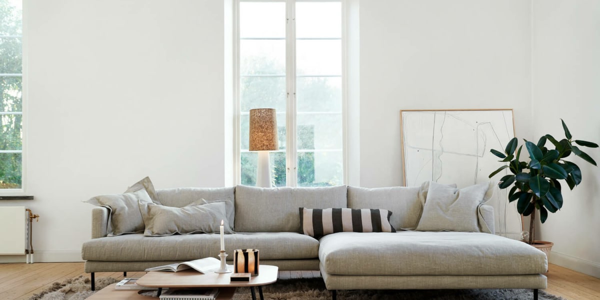 61cedbdea77d740cc589693b_1_BRITT_interior_set2_caleido_stampato_1_natur_1 Un salon avec un canapé en cuir marron, une table basse en marbre et des accents dorés.