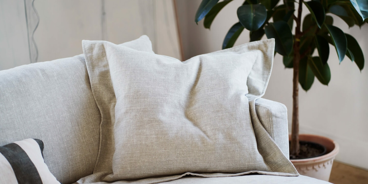 61cedbeb5599ff1fa429b030_3_BRITT_interior_set2_caleido_stampato_1_natur_6 Un espace contemporain avec un canapé en cuir blanc, un sol en bois sombre et des accessoires minimalistes.