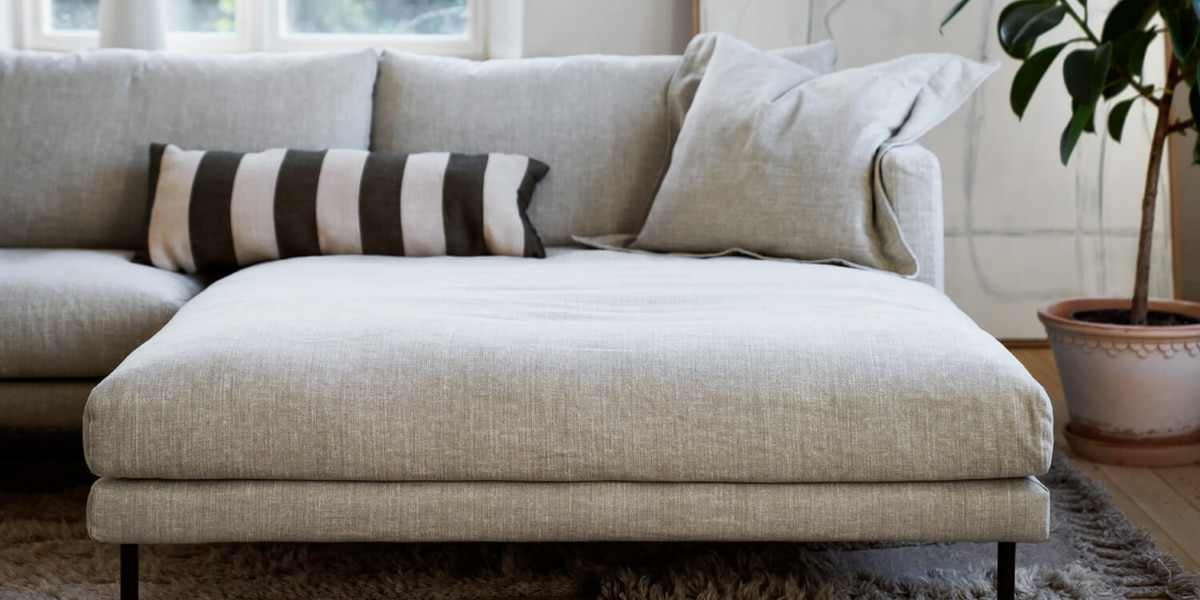 61cedbf0050f4d0049f85e25_4_BRITT_interior_set2_caleido_stampato_1_natur_2 Un salon classique avec un canapé en tissu à rayures, une table basse en bois massif et des chandeliers.