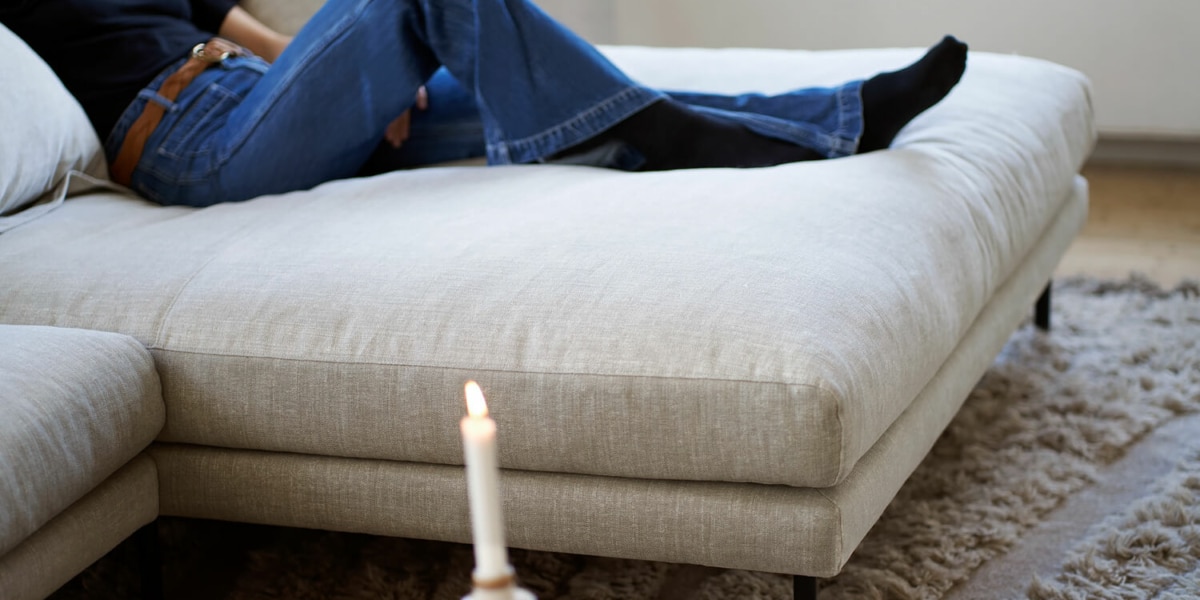 61cedbf7b9b6987f248359de_5_BRITT_interior_set2_caleido_stampato_1_natur_7 Une décoration élégante avec un canapé en lin beige, des rideaux en lin blanc et des accessoires en métal doré.