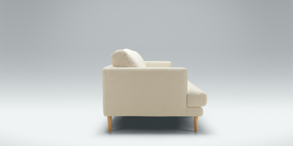 61cedc1ebe32b164cbf04d4a_11_BRITT_studio_4seater_poodle_1_cream_3 Un espace avec un canapé en velours bleu, des rideaux assortis et des œuvres d'art abstraites.