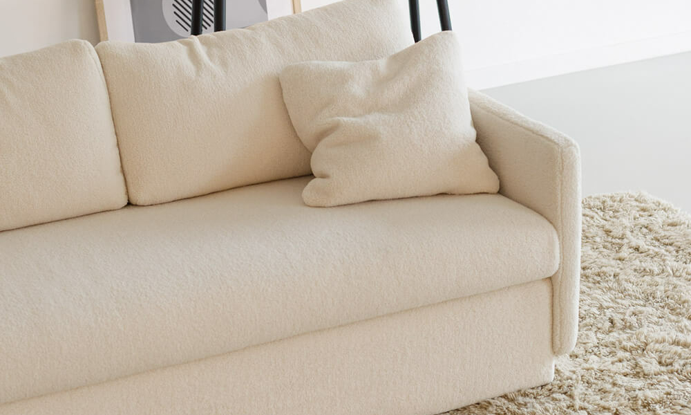 Canapé convertible en lit Colin en blanc dans un salon lumineux avec des accents de beige Placé dans un salon lumineux, le canapé Colin en blanc est accentué par des coussins beige, ajoutant une touche de chaleur à l'espace.