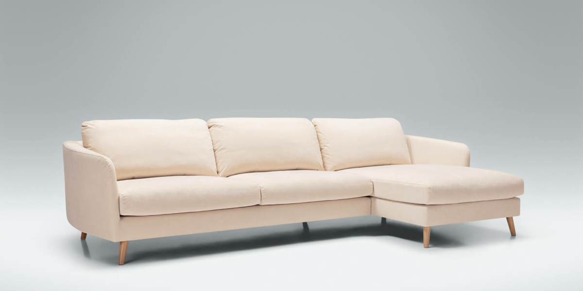 Canapé en L de couleur crème avec pieds en bois sur fond gris, incarnant à la fois élégance et qualité. Canape Paris by Atelier Bis
