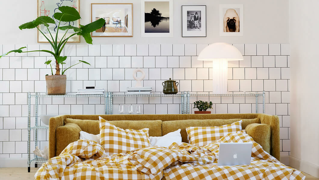 Canapé convertible en lit Stina en cuir marron foncé avec des draps blancs Le canapé Stina en cuir marron foncé est préparé comme un lit avec des draps blancs, prêt à accueillir les invités pour une nuit confortable.