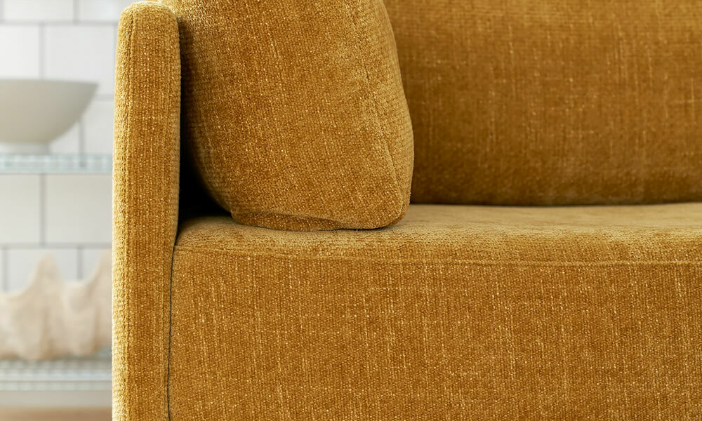 Canapé convertible en lit Stina en tissu marron clair avec des coussins jaunes éclatants Le canapé Stina en tissu marron clair est mis en valeur par des coussins jaunes éclatants, apportant une touche de couleur vive à l'espace.