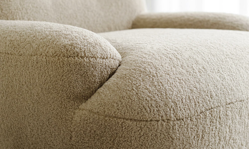 61cedea9bda4b05a89cb3faf_3_UMA_interior_armchair_poodle_1_cream_3 Fauteuil Uma en tissu marron avec des rideaux blancs et jaunes Le fauteuil en tissu marron est placé près de rideaux blancs et jaunes, apportant une touche harmonieuse à la décoration du salon.