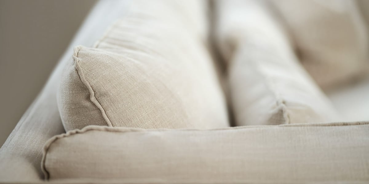 61cedf35c82790f5770c2ae9_3_VIDAR_3,5seater_timber_6_cream_3 Canapé Vidar marron avec des étagères blanches et des accessoires en cuivre Le canapé est entouré d'étagères blanches contenant des livres et des objets décoratifs. Des accessoires en cuivre, comme des lampes et des cadres, ajoutent une touche sophistiquée au salon lumineux.