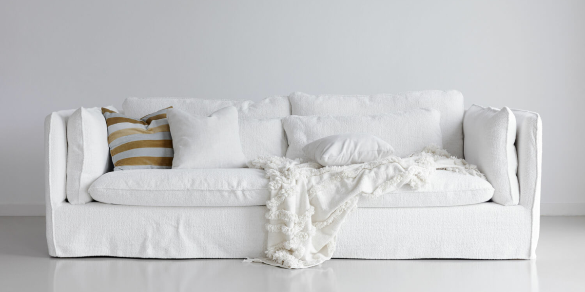 61cedf3a65c416cb07c9884d_4_VIDAR_interior_3,5seater_sky_1_off-white_1 Canapé Vidar blanc avec des plantes vertes et des étagères murales Le canapé est entouré de plantes vertes disposées stratégiquement autour du salon. Des étagères murales blanches exposent des livres et des objets décoratifs, ajoutant une touche personnelle à l'espace.