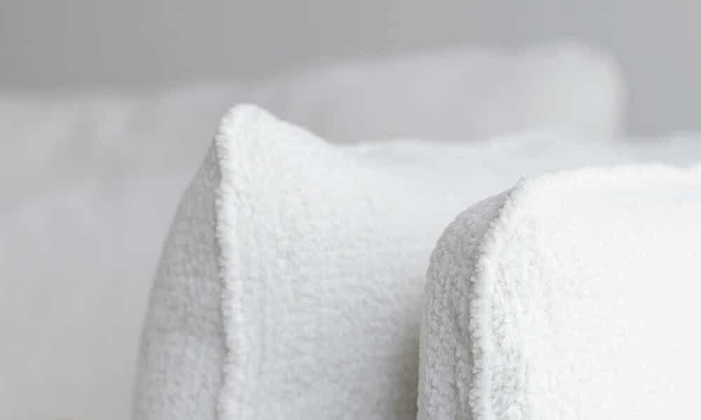 61cedf3df4dde0ec813e81ed_6_VIDAR_interior_3,5seater_sky_1_off-white_4 Canapé Vidar blanc dans un salon avec des murs gris clair et des accents dorés Le canapé se trouve dans un salon aux murs gris clair, avec des touches décoratives dorées comme des lampes et des cadres. La lumière naturelle illumine la pièce, mettant en valeur les tons neutres et les accents métalliques.