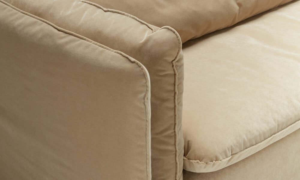 61cedf44bda4b03905cb4208_9_VIDAR_studio_2seater_classic_velvet_24_warm_beige_6 partie du coude du canapé vidar de 3/4 dans un fond blanc, modèle marron