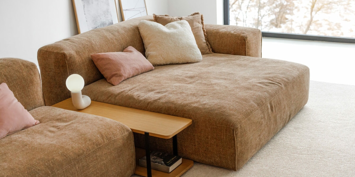 61f964398914d641b3057edc_2_EDDA Un salon scandinave avec un canapé gris clair, des coussins en lin et un tapis en jute.