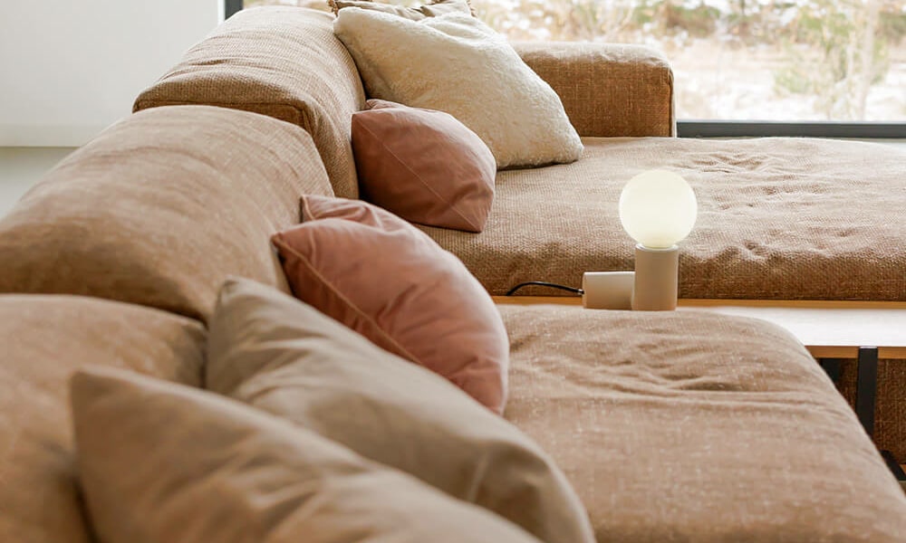 61f9643cf8c2013fd6789a43_3_EDDA Un salon moderne avec un canapé en cuir blanc, des accessoires en bois clair et des plantes vertes.