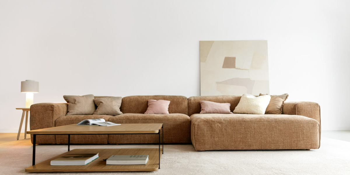 61f9643f24c462247e153943_4_EDDA Un salon avec un canapé en tissu beige, des coussins colorés et une table basse en métal noir.