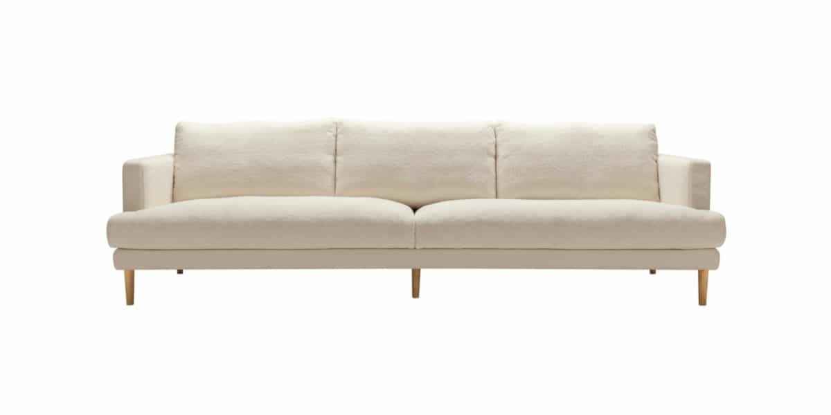 BRITT_technical_4seater_poodle_1_cream_1 Un espace rustique avec un canapé en cuir marron vieilli, des poutres en bois apparentes et un tapis berbère.