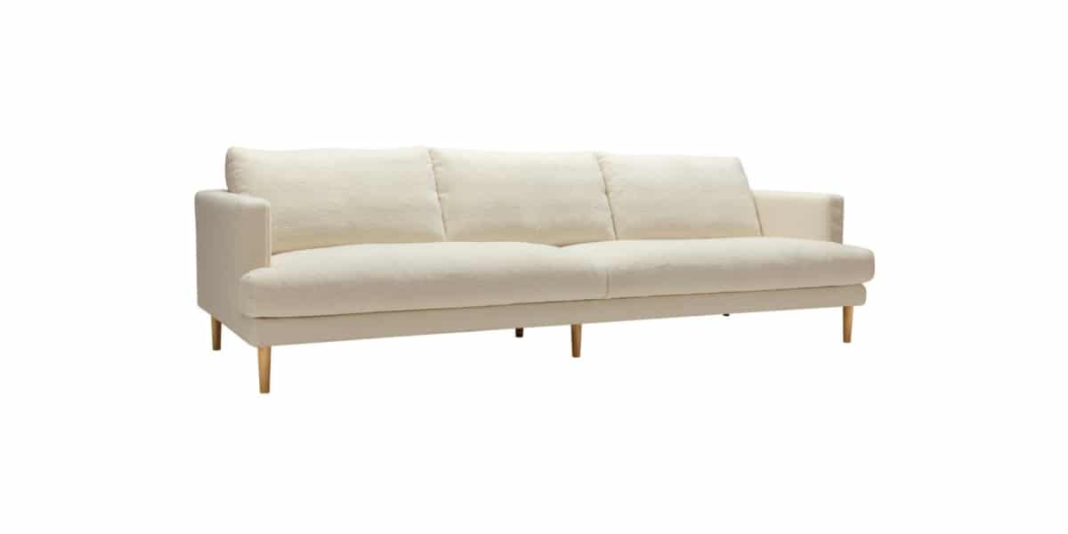 BRITT_technical_4seater_poodle_1_cream_2 Un salon avec un canapé en tissu crème, des étagères flottantes et des œuvres d'art contemporain.