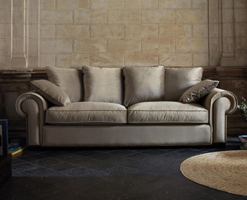 Découvrez l'essence de l'élégance parisienne avec ce canapé beige, doté de trois coussins posés contre un mur en pierre texturée. Posé sur un sol sombre et complété par un tapis rond, il incarne la qualité que vous attendez d'un showroom haut de gamme. Canape Paris by Atelier Bis