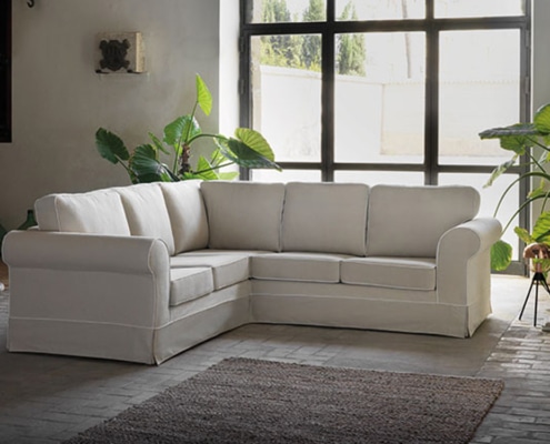 Un canapé sectionnel blanc orne une pièce lumineuse avec de grandes fenêtres et des plantes vertes, mettant en valeur l'élégance de qualité salle d'exposition. Canape Paris by Atelier Bis