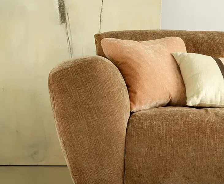 ASTA_SITS_canape-paris_05 Une image du canapé Asta marron dans un salon de style classique avec des rideaux en velours et des tapis persans pour une atmosphère élégante et intemporelle.