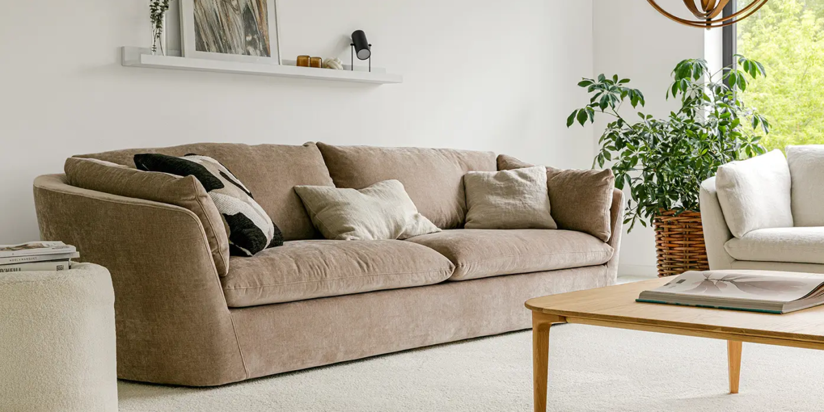 BONNIE_SITS_canape-paris_04 Une photo du canapé Bonnie dans un salon de style rustique avec un tapis en jute et des coussins en lin pour une ambiance chaleureuse et naturelle.