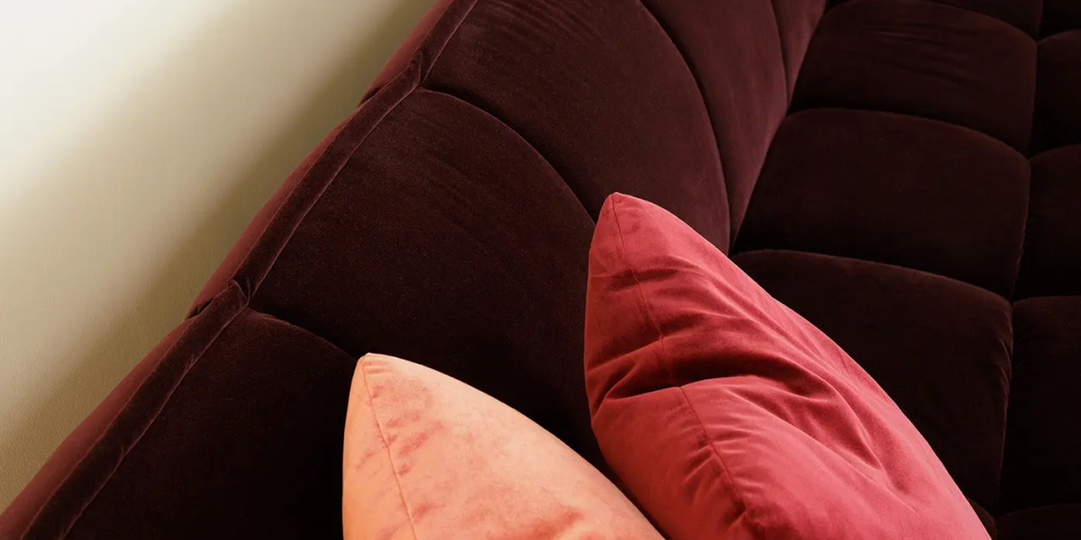 CLYDE_SITS_canape-paris_06 Une photo du canapé rose dans un salon élégant avec des rideaux en velours et des accents dorés pour une ambiance luxueuse et sophistiquée.