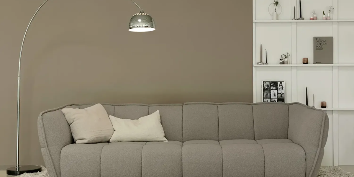 CLYDE_SITS_canape-paris_07 Une image du canapé Clyde gris avec des coussins et une couverture en fausse fourrure pour une ambiance chaleureuse et confortable.