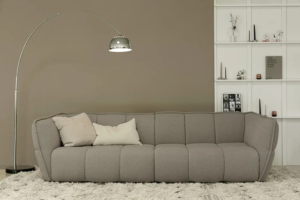 Une image du canapé Clyde gris avec des coussins et une couverture en fausse fourrure pour une ambiance chaleureuse et confortable.