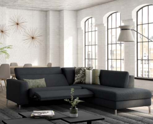 Salon moderne avec canapé d'angle gris foncé, table basse et grandes fenêtres qui mettent en valeur l'élégance. Coin repas visible en arrière-plan, rappelant un showroom parisien où la qualité rencontre le style. Canape Paris by Atelier Bis