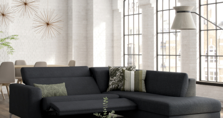 Salon moderne avec canapé d'angle gris foncé, table basse et grandes fenêtres qui mettent en valeur l'élégance. Coin repas visible en arrière-plan, rappelant un showroom parisien où la qualité rencontre le style. Canape Paris by Atelier Bis